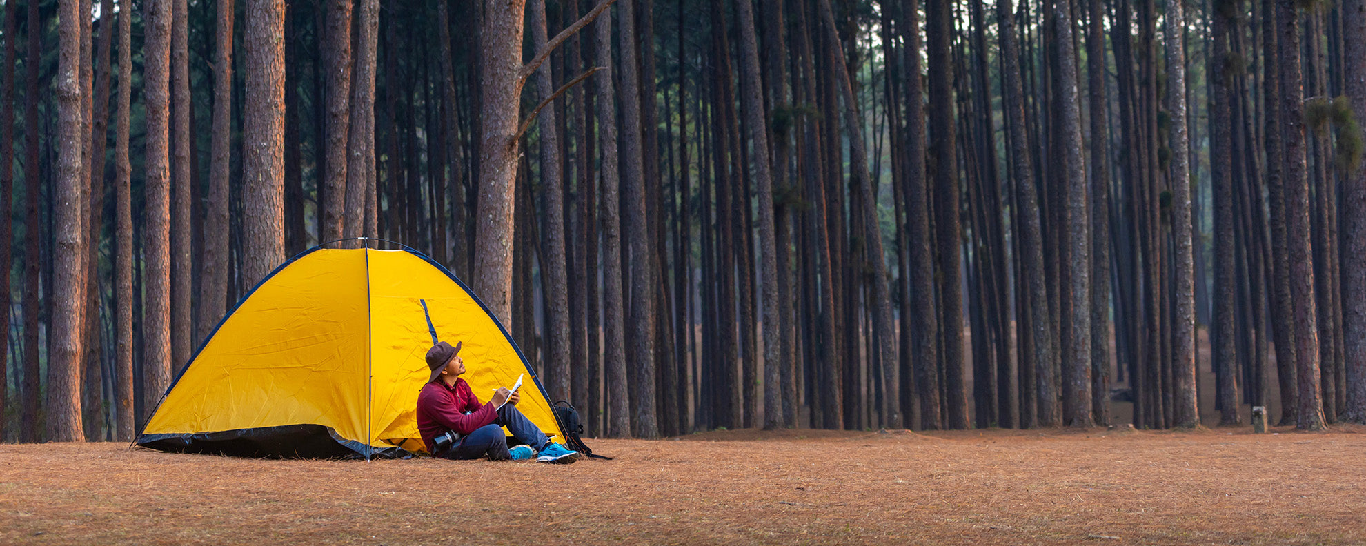 Man sitting in front of a tent in the woods